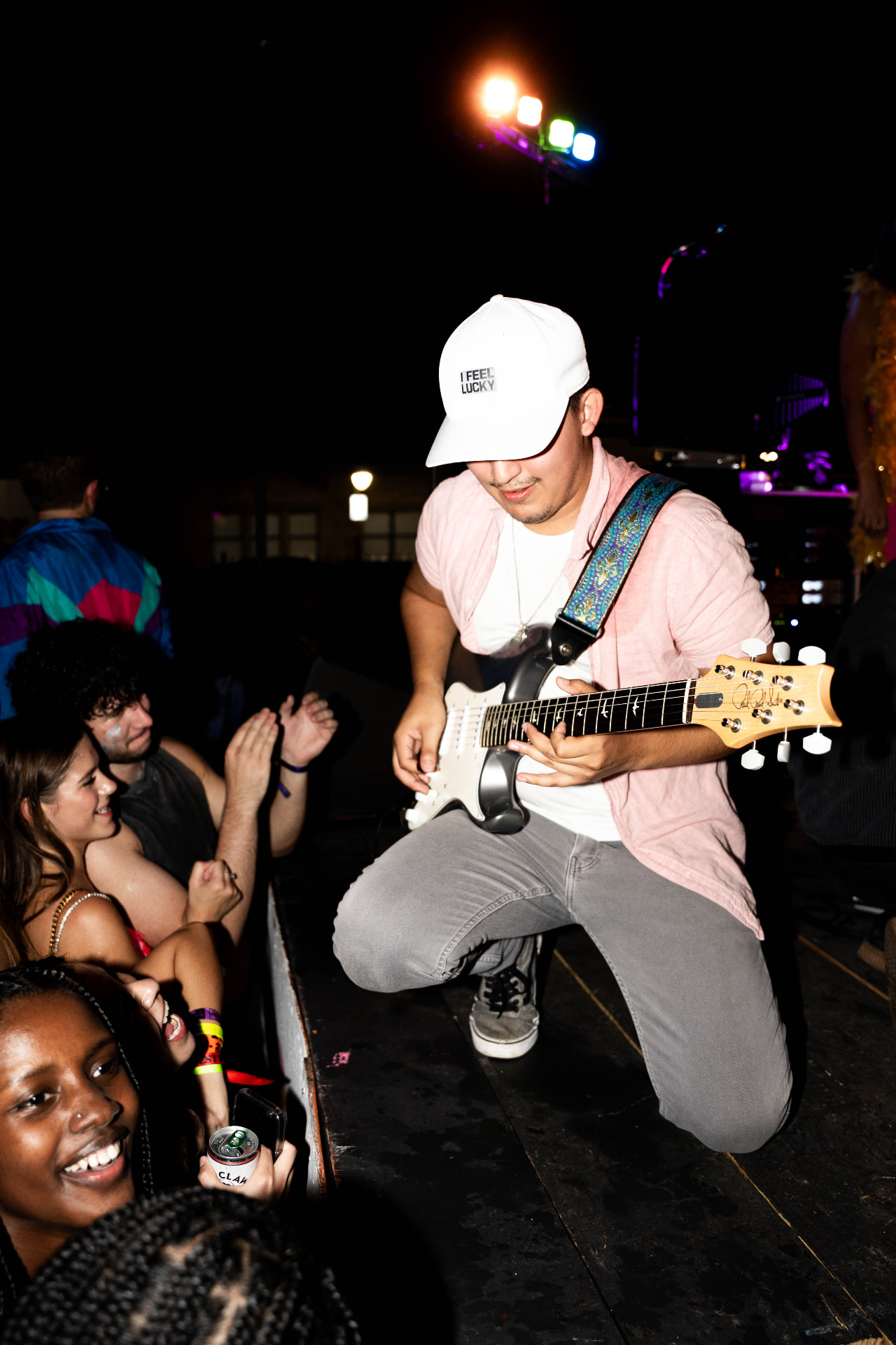 Guitarist crouched at the stage edge playing to students in the front row