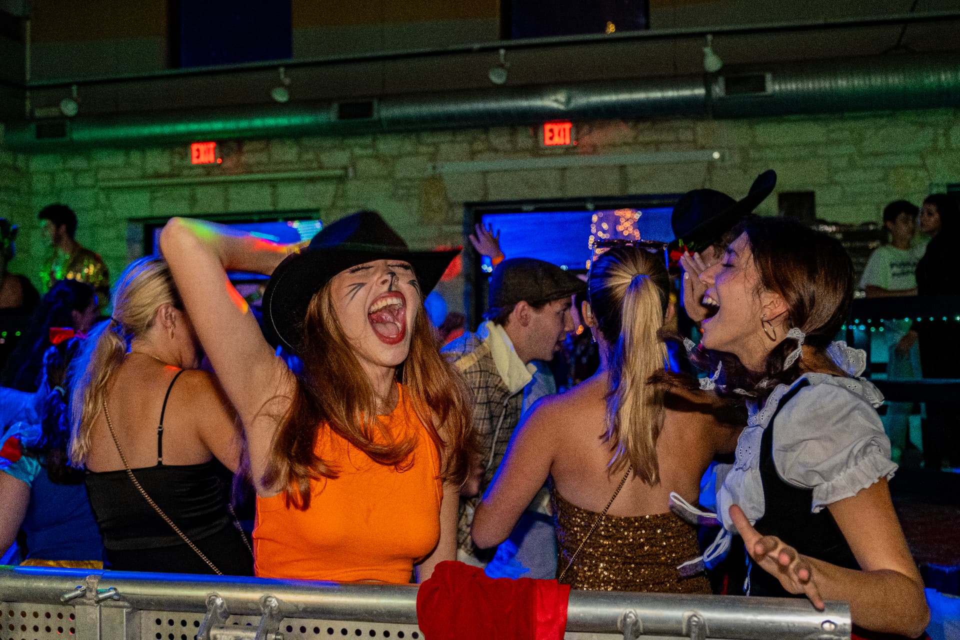 Students singing along on a packed dance floor under coloured lights