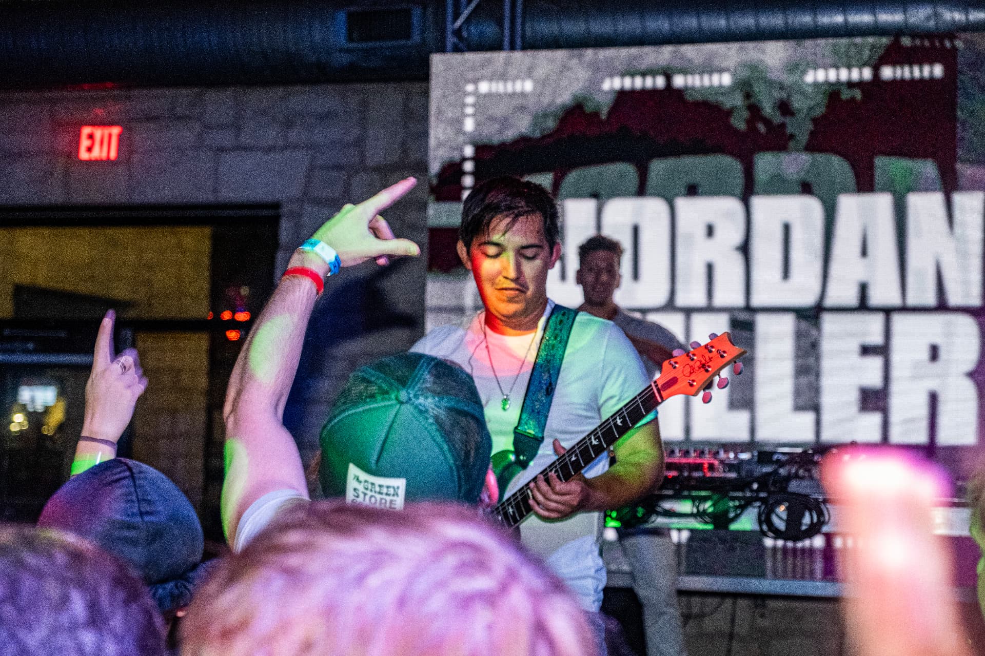 Guitar solo in front of an LED wall with student hands raised in the crowd