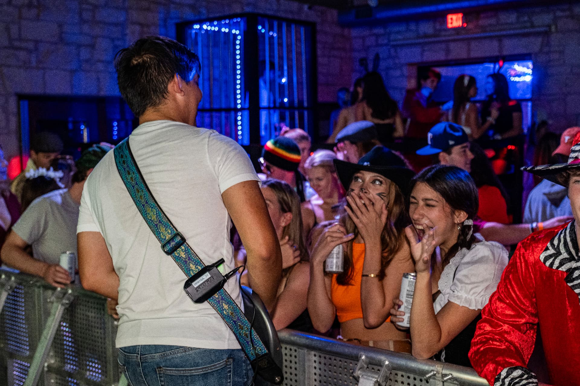 Live electric guitarist playing over the barricade to students on the front rail
