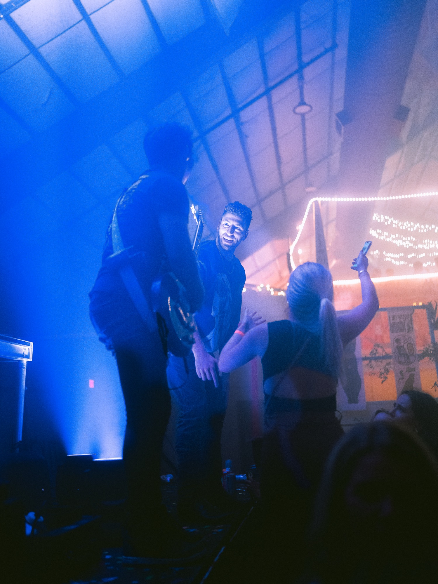 Mixmode playing a fraternity show under blue stage light with students filming from the floor