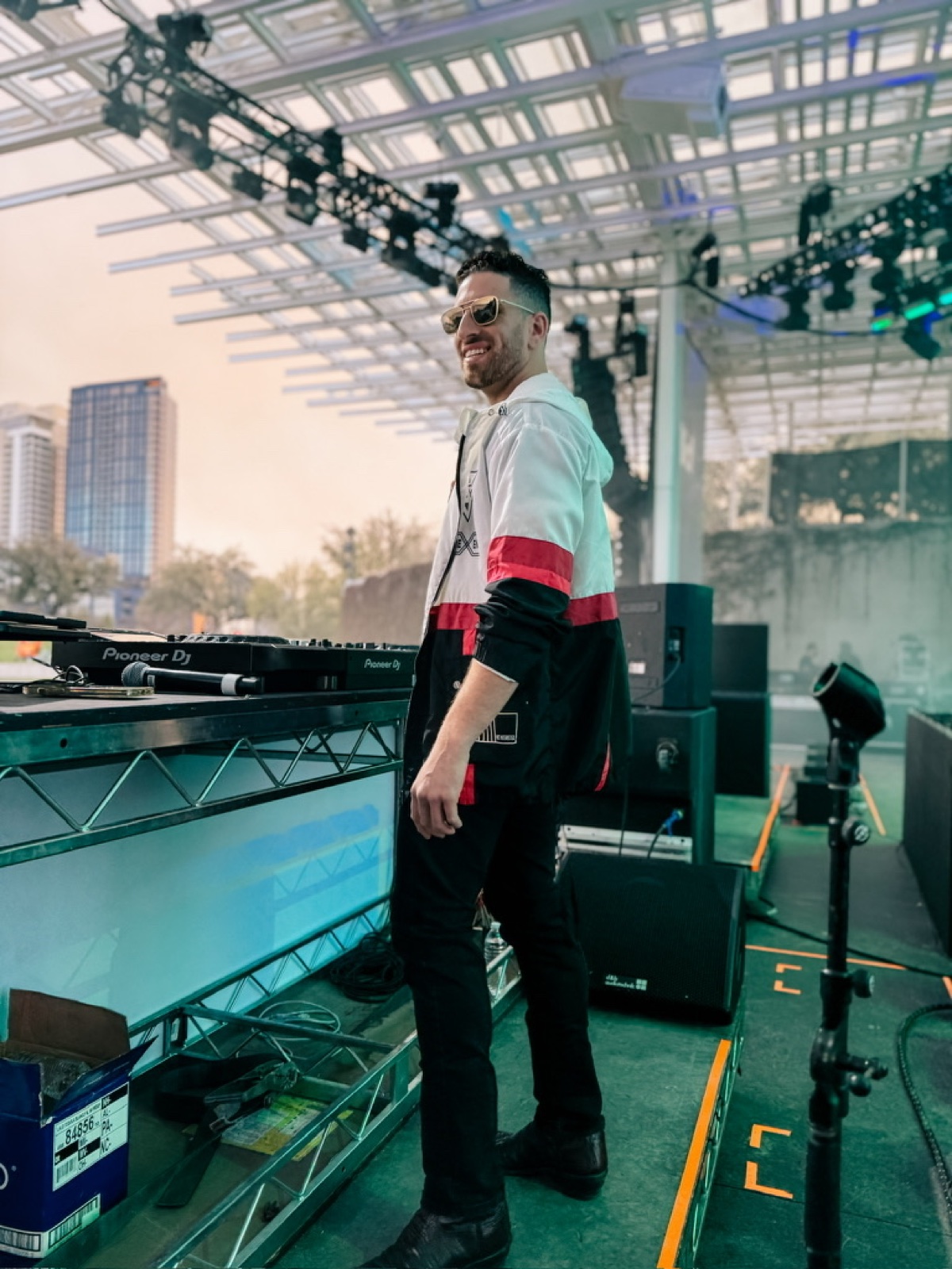 Jordan Miller on the SXSW stage in Austin beside Pioneer decks, city skyline behind the rig