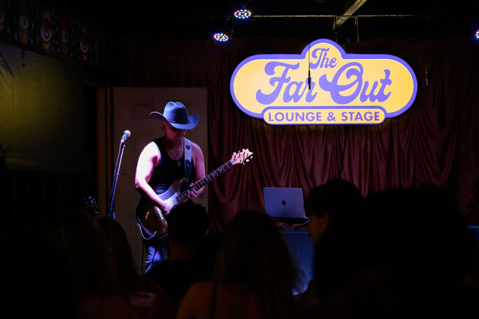 Kristian Cruz on guitar under The Far Out Lounge sign in Austin