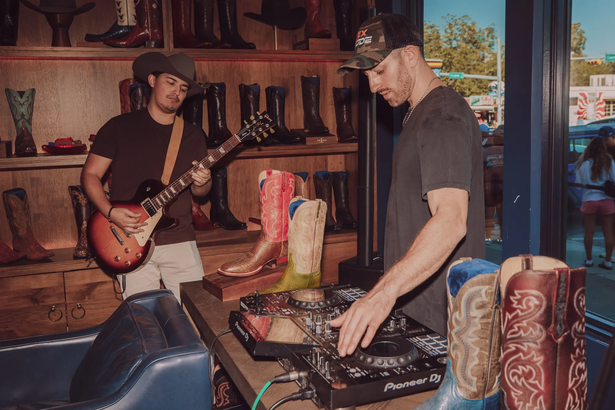 Kristian Cruz playing electric guitar beside Jordan Miller at the DJ decks inside the Lucchese boot store on South Congress.